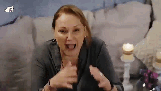 a woman is sitting on a couch making a funny face with her mouth open .