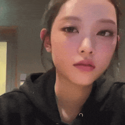 a close up of a woman 's face wearing a black hoodie and looking at the camera .