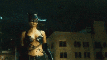 a woman in a catwoman costume is standing in a dark city at night .