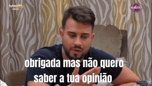 a man with a beard is sitting on a couch with the words obrigada mas nao quero saber a tua opinion