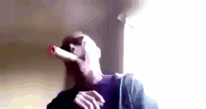 a man is smoking a cigar in front of a window while wearing sunglasses .