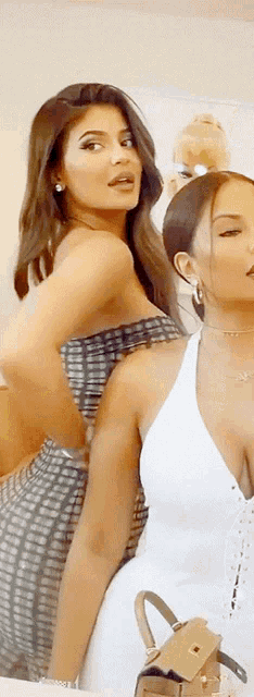 two women standing next to each other with one wearing a white top