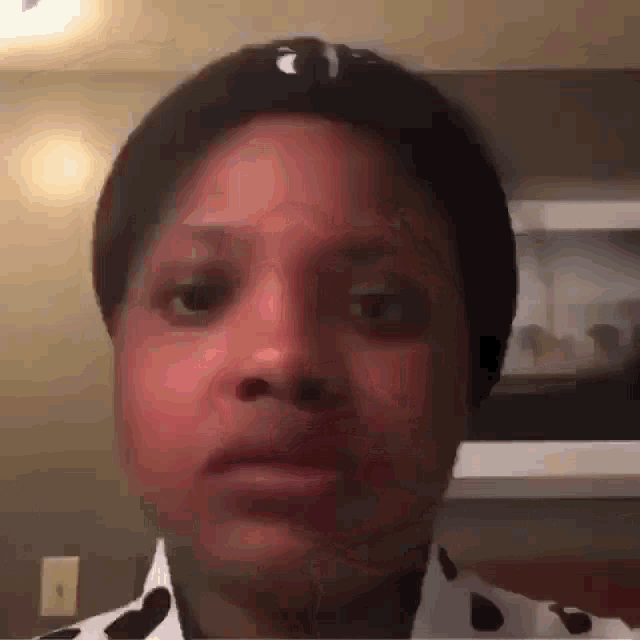 a close up of a person 's face with a polka dot shirt on
