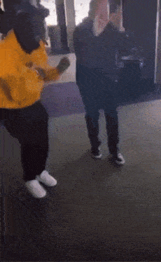 a man in a yellow jacket is dancing with another man in a black shirt
