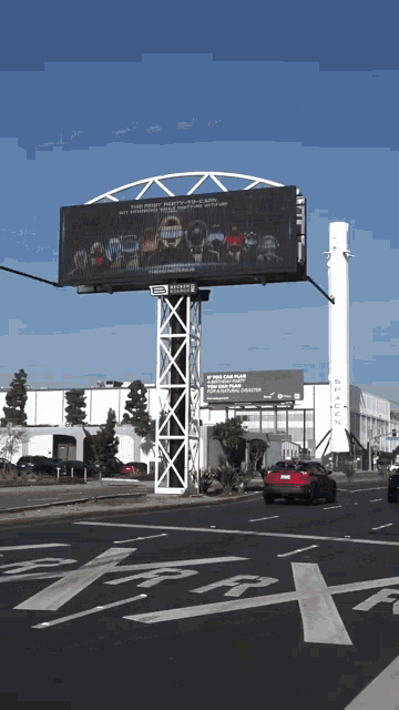 a large billboard on the side of a road that says ' tesla ' on it