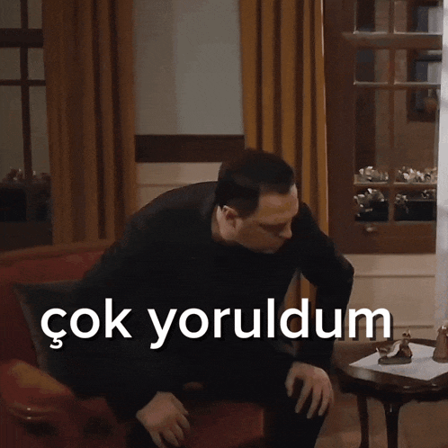 a man sits on a couch with the words çok yoruldum written on the bottom