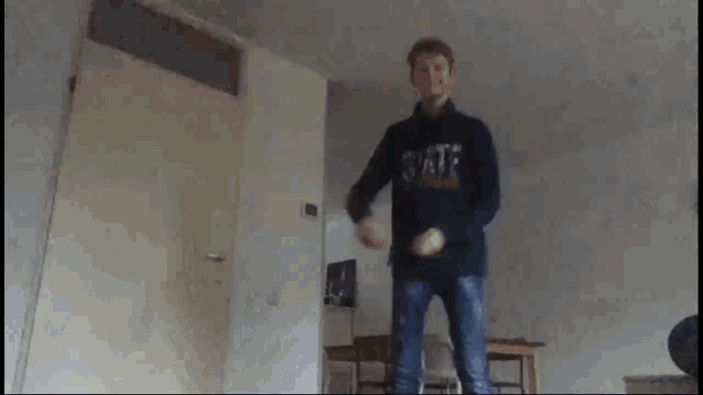 a blurry picture of a man dancing in a living room with the letters t on his shirt