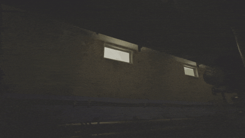 a dark room with a few windows and a pipe
