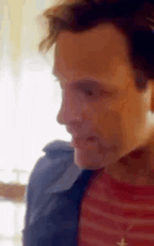 a close up of a man 's face with a striped shirt on .