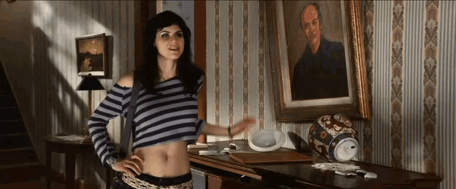 a woman in a striped shirt stands in front of a painting