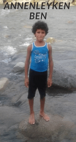 a young boy in a blue tank top stands on a rock near a river with the name anneleyken ben written above him