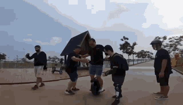 a group of people are standing around a man riding a scooter .