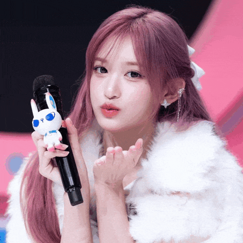 a woman blowing a kiss while holding a microphone
