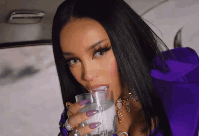a woman with purple nails is drinking from a glass