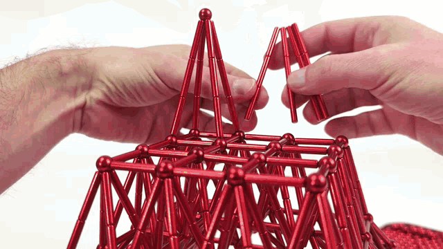 a person is playing with red sticks and balls on a white background