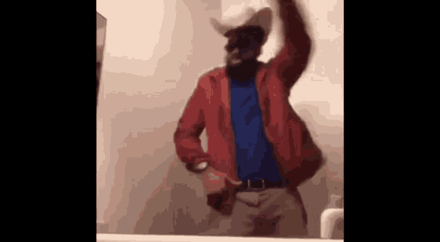 a man in a red jacket and cowboy hat is dancing in front of a bathroom mirror