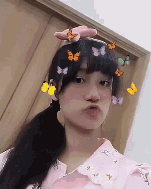 a girl with a pink bow on her head has butterflies around her face