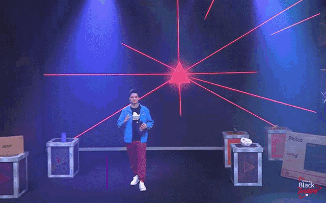a man in a blue jacket stands in front of a large screen with the name felipe ne on it
