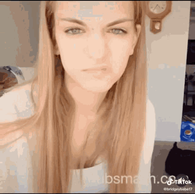 a woman is making a funny face in front of a clock that says tiktok