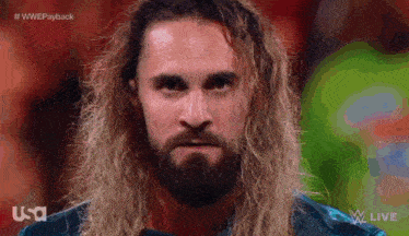 a man with long hair and a beard looks at the camera with the words #wwepayback on the bottom