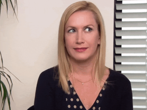a woman with blonde hair and a polka dot top looks to the side