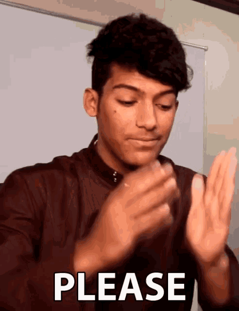 a young man is clapping his hands in front of a white board that says please