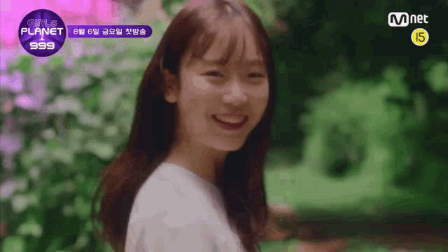 a girl is smiling and looking at the camera while standing in a garden .