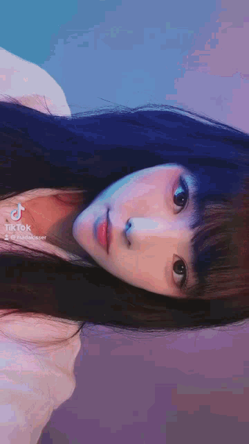 a girl with long black hair has a tiktok sticker on her shoulder