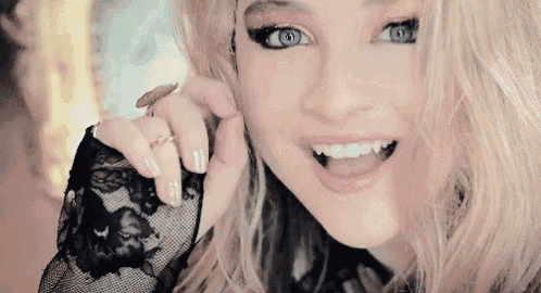 a close up of a woman 's face with blue eyes and a black lace top .