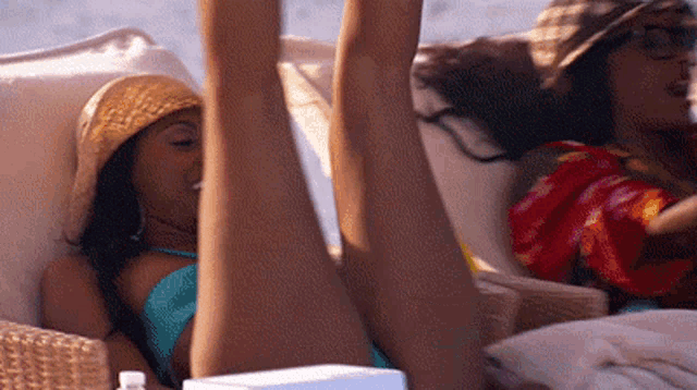 a woman in a blue bikini is laying on a beach chair with her legs up
