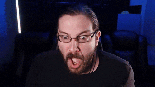 a man with a beard and glasses is making a funny face .