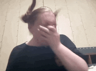 a woman is covering her face with her hands while wearing a headband .