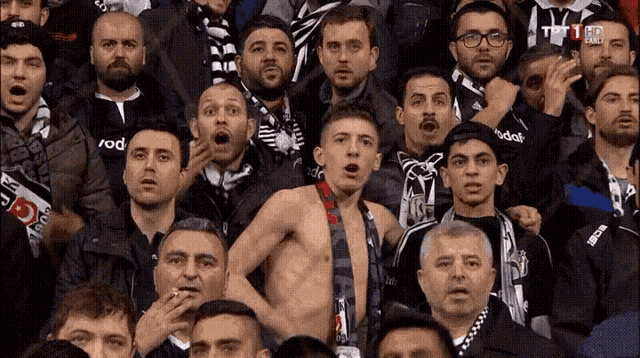 a shirtless man stands in a crowd of people with a scarf that says voda on it