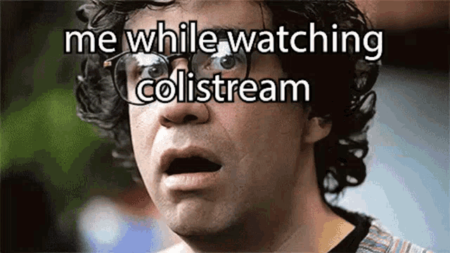 a man wearing glasses is making a funny face while watching a video on colistream .