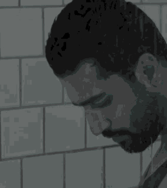 a black and white photo of a man with a beard looking down