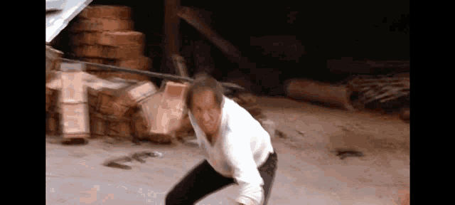 a man in a white shirt and black pants stands in front of a pile of boxes