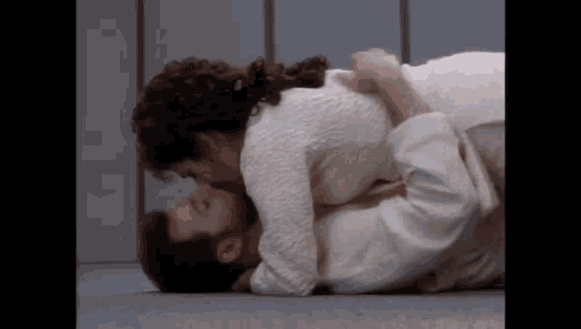 a man and a woman are kissing on the ground