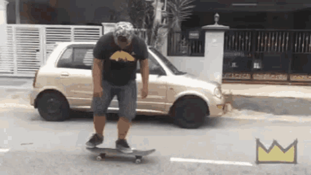 a man in a batman shirt is riding a skateboard on the street