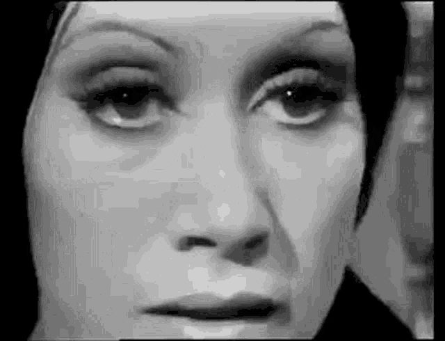 a black and white photo of a woman 's face looking at the camera .
