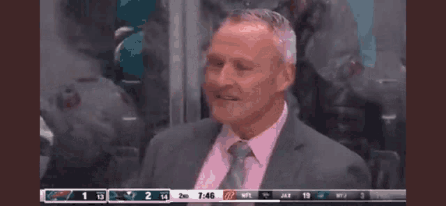 a man in a suit and tie is sitting in the stands watching a game .