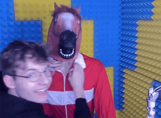 a man wearing a horse mask is being touched by another person