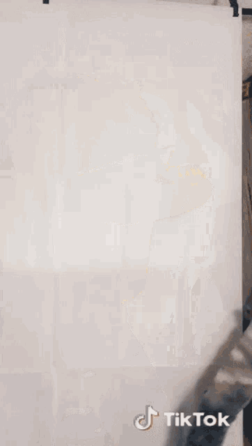 a woman in a yellow crop top is dancing in front of a white wall with a tiktok sticker on it