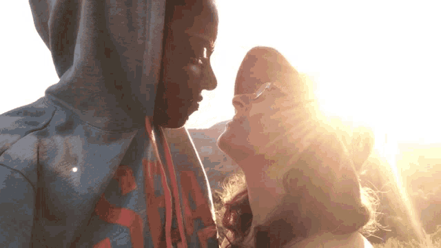 a man wearing a hoodie with the letter a on it kisses a woman