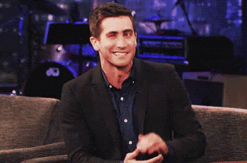 a man in a suit is sitting on a couch with his hands in his pockets