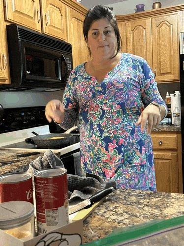 a woman cooking in a kitchen with a can of tomato soup