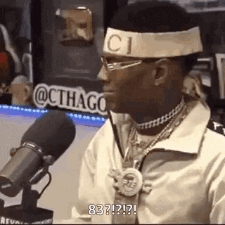 a man is sitting in front of a microphone wearing a headband with the word gucci on it .