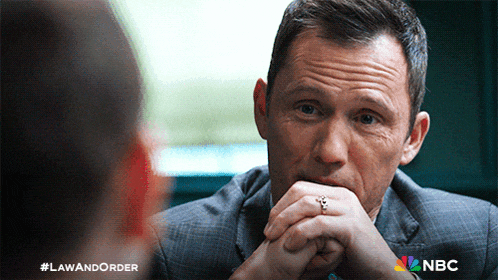 a man with a ring on his finger sits in front of a nbc ad