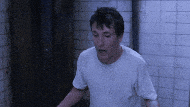 a man in a white shirt is standing in a bathroom