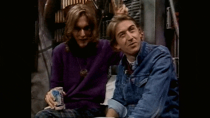 two men are sitting next to each other and one is holding a beer can .
