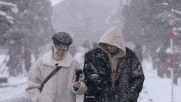 a man and a woman are standing in the snow . the man is holding a camera .
